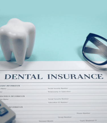 Dental insurance form with tooth model and protective eyewear on blue background