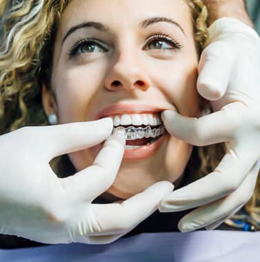 Patient receiving orthodontic examination with dental professional adjusting braces in clinical setting.