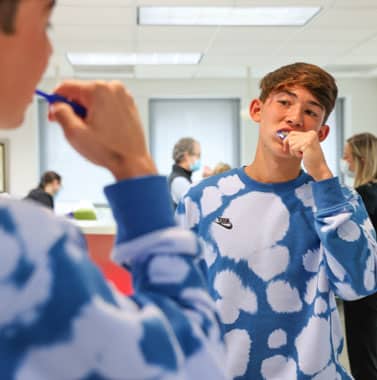 Young patient examining teeth in orthodontic office mirror during dental consultation.