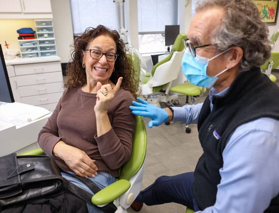 Orthodontist adjusting braces on female patient in dental office treatment chair.