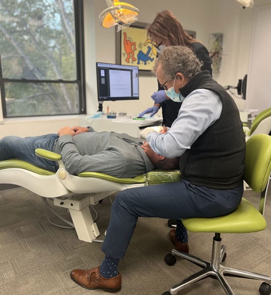 Orthodontist examining patient's teeth model in modern dental office treatment room.