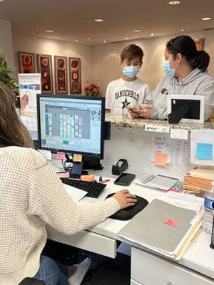 Patient at reception desk during orthodontic appointment check-in at Toombs Orthodontics office.