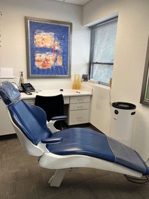 Dental treatment room with blue orthodontic chair, desk, and window at Toombs Orthodontics.