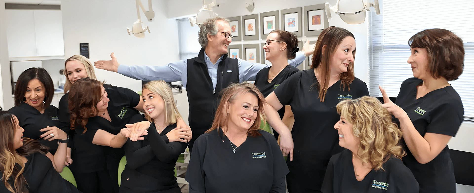 Orthodontics team members in black uniforms laughing and bonding together in office setting.