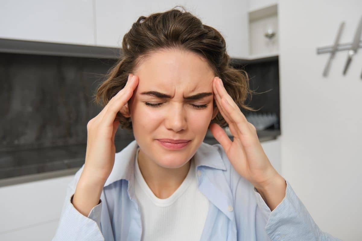 Woman holding her temples in pain, illustrating headaches caused by bite problems.